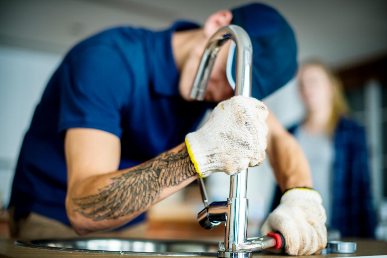Plumber working on a kitchen faucet connection