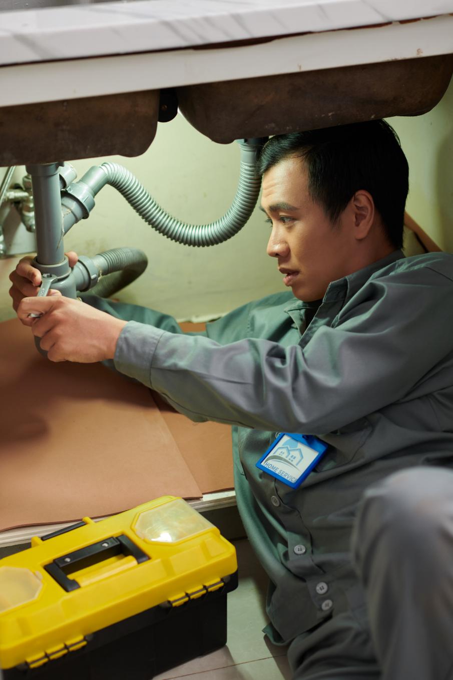 Plumber tightening a sink trap beneath a counter