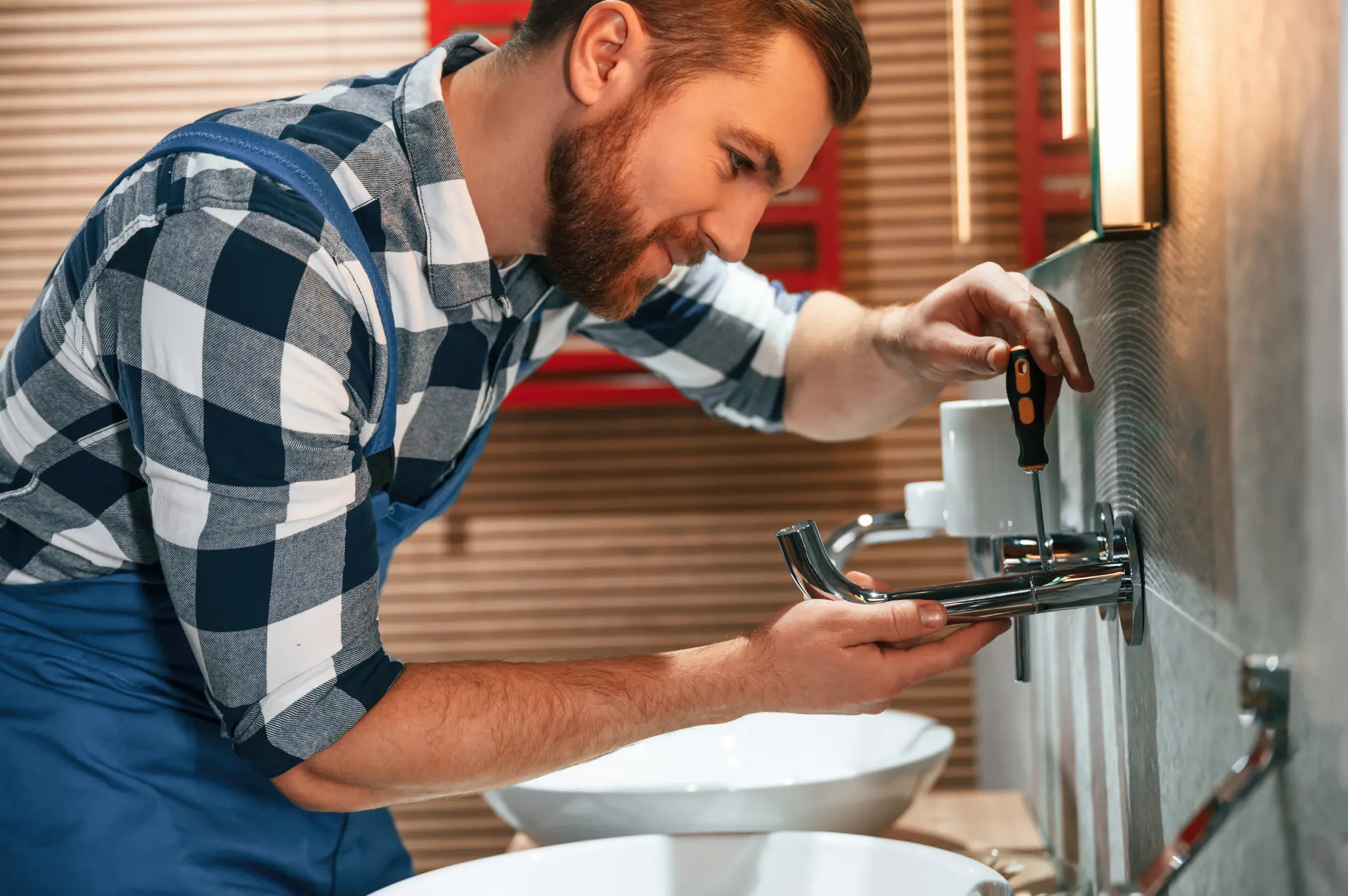Plumber repairing a bathroom faucet with a screwdriver